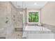 Luxurious bathroom featuring a separate glass shower, a soaking tub, and a serene view of the surrounding greenery at 200 Camp Creek Trail, Peachtree City, GA 30269