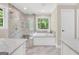 Bright bathroom features a glass-enclosed shower, a soaking tub, and dual vanities with marble countertops at 200 Camp Creek Trail, Peachtree City, GA 30269