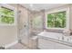 Spa-like bathroom featuring glass shower, soaking tub, and a large window offering natural light and tranquil outdoor views at 200 Camp Creek Trail, Peachtree City, GA 30269