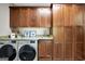 Well-equipped laundry room with granite countertops, modern washer, dryer, and wooden cabinets for organized storage at 200 Camp Creek Trail, Peachtree City, GA 30269