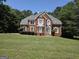 Charming two-story brick home with a well-manicured lawn and mature trees on a sunny day at 308 Bell Isle, Mcdonough, GA 30252