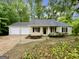 A charming tan home with a two-car garage and black shutters on the windows at 6026 Woodcreek Dr, Woodstock, GA 30188