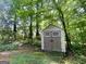 Small outdoor shed on a wooded property with greenery surrounding the structure at 6026 Woodcreek Dr, Woodstock, GA 30188