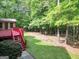 A backyard featuring a brick house, a bright red deck, and luscious trees at 428 Turner Rd, Mcdonough, GA 30252