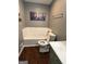Bathroom featuring white tiled bathtub, toilet, decorative artwork, and grey walls at 223 Rivers Rd, Fayetteville, GA 30214