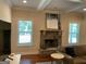 Cozy living room showcasing a stone fireplace and mantle, complemented by natural light from two windows at 101 Elkins Blvd, Locust Grove, GA 30248