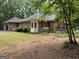 Rear exterior showcasing a brick home with a sunroom, side-entry garage, and private backyard setting at 115 Stable Creek Rd, Fayetteville, GA 30215