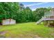 Expansive backyard view showing a storage shed and home with porch, set against a backdrop of mature trees at 3777 Edward Rd, Rex, GA 30273