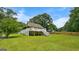 Well-maintained backyard featuring lush grass, mature trees, and a charming house with a covered porch at 3777 Edward Rd, Rex, GA 30273