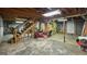 Spacious unfinished basement with exposed beams, concrete floor, and a wooden staircase at 3777 Edward Rd, Rex, GA 30273