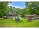 Expansive front yard showcasing the home, detached garage, carport, and lush greenery on a sunny day at 3777 Edward Rd, Rex, GA 30273