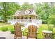 Home's front exterior with a white porch, mature trees and patio seating at 3777 Edward Rd, Rex, GA 30273