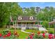 Charming two-story home featuring a welcoming front porch with white railings surrounded by colorful flowers at 3777 Edward Rd, Rex, GA 30273