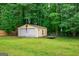 Backyard view featuring a large storage shed with two garage doors and a trailer, surrounded by mature trees at 3777 Edward Rd, Rex, GA 30273