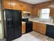 A well-lit kitchen featuring wooden cabinets, stainless steel sink, black appliances and wood-look floors at 133 Deerfield Ln, Carrollton, GA 30116
