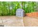 Backyard shed with a concrete foundation, neutral paint and surrounded by trees and lush plants at 10 Queens Ct, Sharpsburg, GA 30277