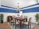 Elegant dining area with wood table, chandelier, and striking blue accent wall at 230 Shorewood Ct, Mcdonough, GA 30252