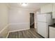 View of the kitchen area with white appliances and access to the staircase, adjacent to a dining space with vinyl floors at 115 Fairview Way, Stockbridge, GA 30281