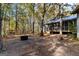 A spacious backyard featuring a wooded backdrop, fire pit, and a house with a screened-in porch at 335 Gum Creek Rd, Roopville, GA 30170