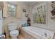 Relaxing bathroom with a soaking tub, neutral tile surround, and two sunlit windows at 335 Gum Creek Rd, Roopville, GA 30170