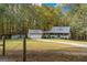 Exterior view of a charming home with a detached garage surrounded by a lawn and wooded area at 335 Gum Creek Rd, Roopville, GA 30170