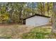 Outbuilding with ample storage and a sheltered overhang, surrounded by forest and grassy yard at 335 Gum Creek Rd, Roopville, GA 30170