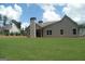 View of rear of house with well-maintained lawn, black trimmed windows, and chimney at 49 Durham Estates Dr, Sharpsburg, GA 30277