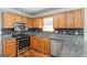 Eat-in kitchen featuring stainless steel appliances, granite counters, and wood cabinets at 1416 Emerald Pine Ct, Lawrenceville, GA 30043