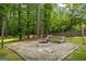 Firepit and bench with gravel surround, lush greenery, and string lights at 171 Ponderosa Drive, Fayetteville, GA 30214