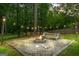Backyard firepit and bench with gravel surround, lush greenery, and string lights at 171 Ponderosa Drive, Fayetteville, GA 30214
