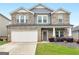 Charming two-story home with a stone and gray siding facade, manicured lawn, and attached garage at 168 Warbler Way, Mcdonough, GA 30253