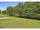 Landscaped backyard featuring lush green grass, trees and a concrete slab at 122 Claxton Ct, Jonesboro, GA 30238