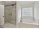 Bathroom showcasing a glass-enclosed shower, soaking tub, and neutral tile at 122 Claxton Ct, Jonesboro, GA 30238