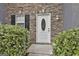 Close up of a charming home entrance with a white front door, stone facade, and manicured greenery at 122 Claxton Ct, Jonesboro, GA 30238