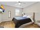 Light-filled bedroom boasts wood floors, a comfortable bed with a cushioned headboard, and a modern ceiling fan at 5284 Benjamin Trl, Ellenwood, GA 30294