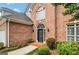 Close up of a brick home's arched doorway with black door, flanked by green shrubs and manicured landscaping at 232 Spalding Gates Drive, Atlanta, GA 30328
