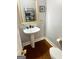 Updated powder room featuring hardwood floors, white pedestal sink, gold faucet, and a framed mirror at 232 Spalding Gates Drive, Atlanta, GA 30328