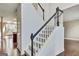 Carpeted staircase featuring white risers, and black handrail, adjacent to hardwood floors and natural light at 232 Spalding Gates Drive, Atlanta, GA 30328