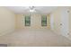 Bright bedroom with neutral carpet, ceiling fan, and two windows offering natural light and a calming view at 200 Whitney Way, Fayetteville, GA 30214