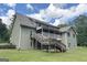 View of the home's back exterior, including a wooden staircase leading to a porch overlooking the expansive backyard at 3133 Callie Still Rd., Lawrenceville, GA 30045