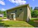 Back of home featuring a small concrete patio, green lawn, and pale green siding at 325 Espana St, South Fulton, GA 30349