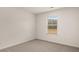 Bright bedroom with neutral carpet and walls, showcasing a window with natural light and outdoor views at 1804 Quaker St, Hampton, GA 30228