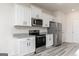 Modern kitchen with granite countertops, stainless steel appliances, white cabinetry and wood-look floors at 458 Prescott Way, Villa Rica, GA 30180