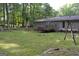 Backyard featuring a spacious deck, fire pit, and a swing set nestled among the trees at 142 Carrollwood Dr, Fayetteville, GA 30215