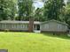 Charming single-story home with a brick chimney, complemented by a lush green lawn and mature trees at 142 Carrollwood Dr, Fayetteville, GA 30215