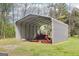 A metal barn shields a tractor with mowing equipment in a grassy field at 270 Morrow Rd, Newborn, GA 30056