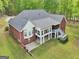 Rear view of a brick two-story house with a screened porch, gray roof and lush backyard at 270 Morrow Rd, Newborn, GA 30056