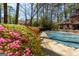 In-ground pool surrounded by lush vegetation including colorful flowering bushes at 9995 Huntcliff Trce, Atlanta, GA 30350