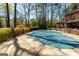 Backyard pool with covered surface surrounded by brick patio and flowering plants, set against a backdrop of mature trees at 9995 Huntcliff Trce, Atlanta, GA 30350