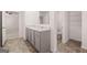 Bright bathroom with double vanity, storage cabinets, toilet, and an open doorway to the bedroom at 1473 Autumn Wind Dr # 25, Dacula, GA 30019